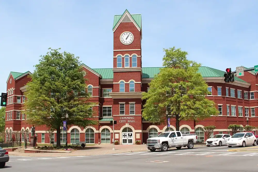 Cumming City Hall, a red brick building with a clock tower, at a street corner in Cumming, Georgia
