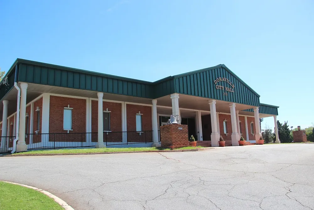 Doraville City Hall, a low brick building with a green roof and white columns, in Doraville, Georgia