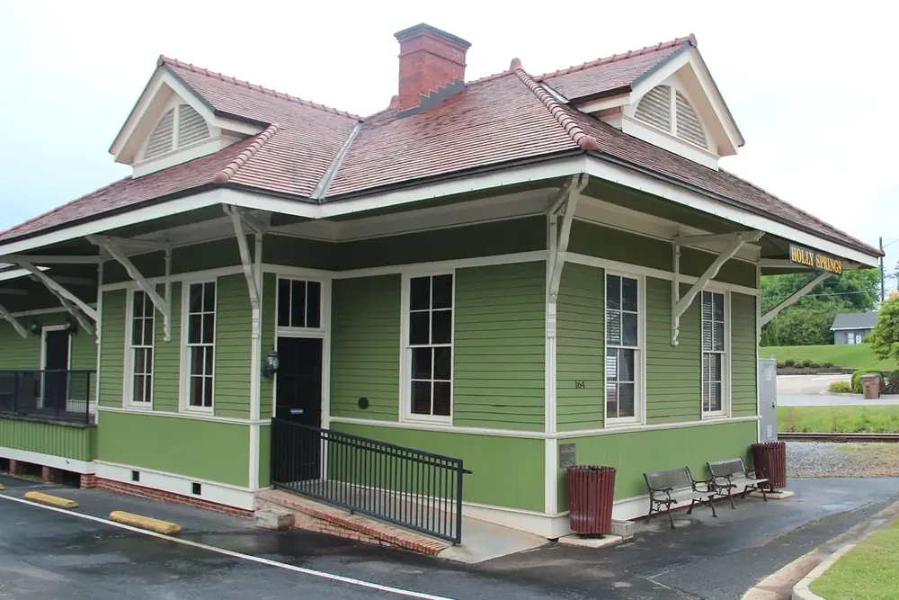 Restored green Holly Springs train depot with a red tile roof in Holly Springs, Georgia