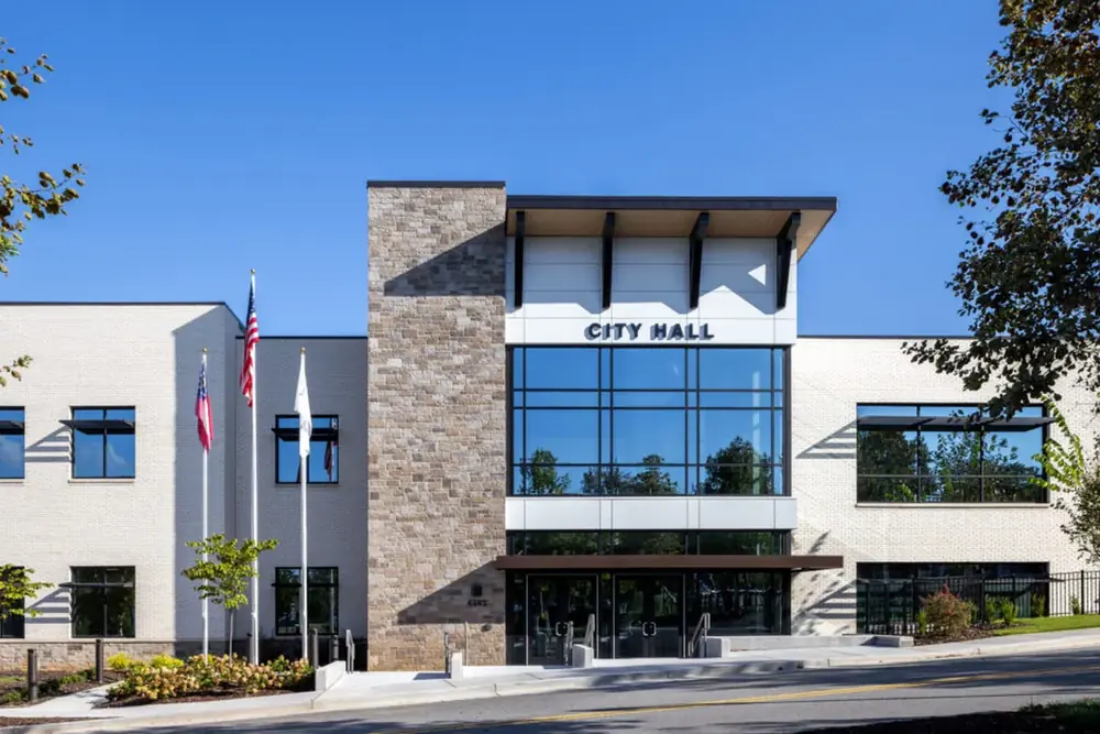 Powder Springs City Hall, a modern building with a glass entrance and flags, in Powder Springs, Georgia