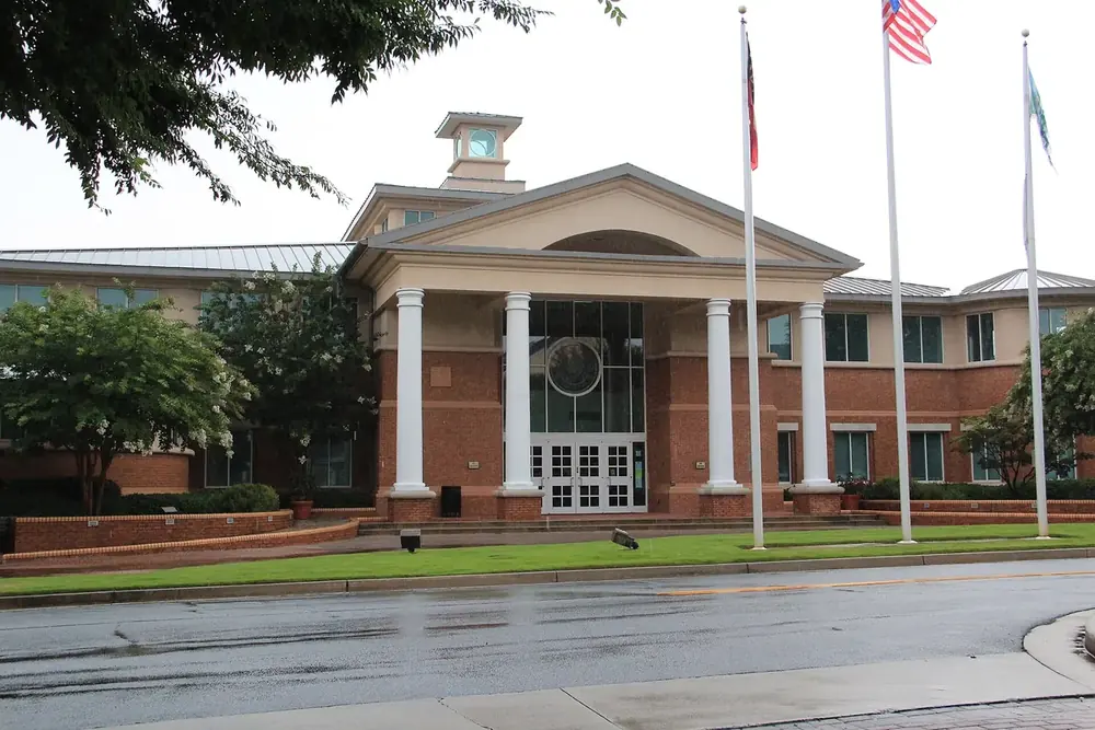 Smyrna City Hall, a columned brick building with three flagpoles, in Smyrna, Georgia